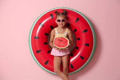 Photo of Cute little girl with inflatable ring and watermelon on color background