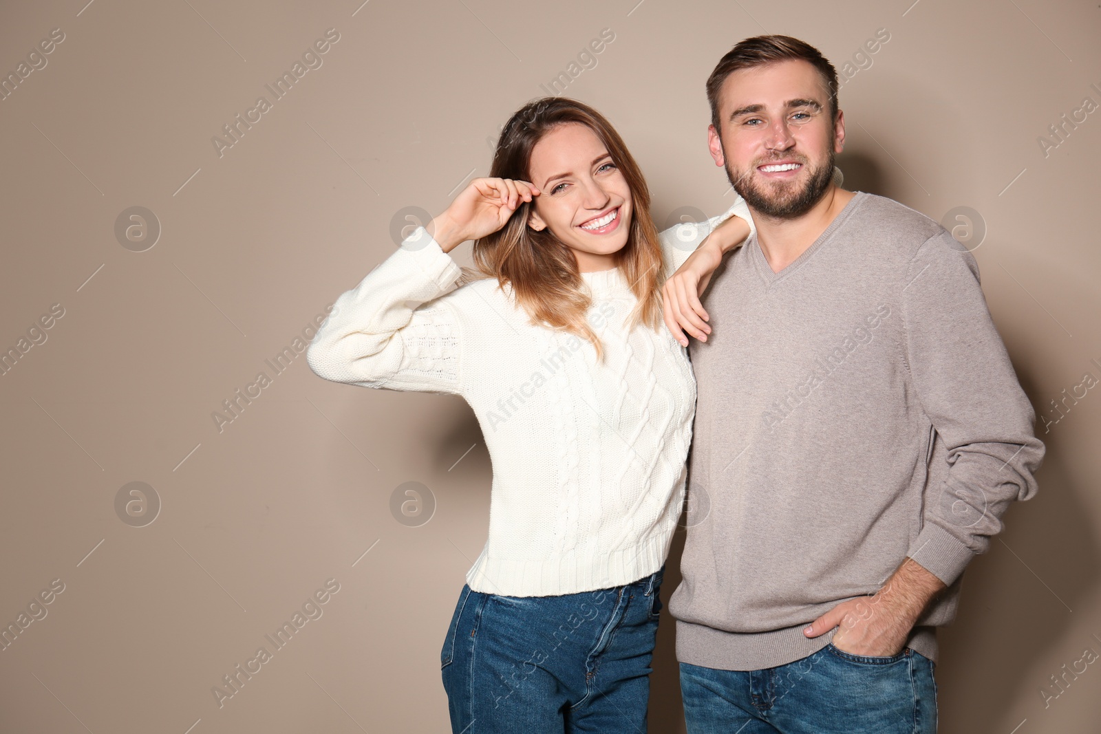 Image of Lovely couple in warm sweaters on beige background 