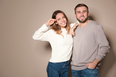 Lovely couple in warm sweaters on beige background 