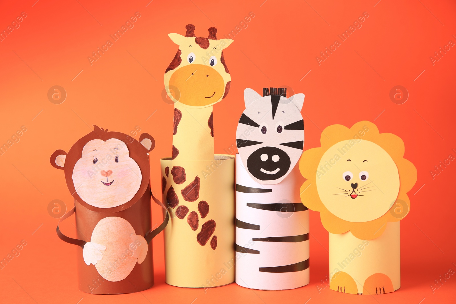 Photo of Toy monkey, giraffe, lion and zebra made from toilet paper hubs on orange background. Children's handmade ideas