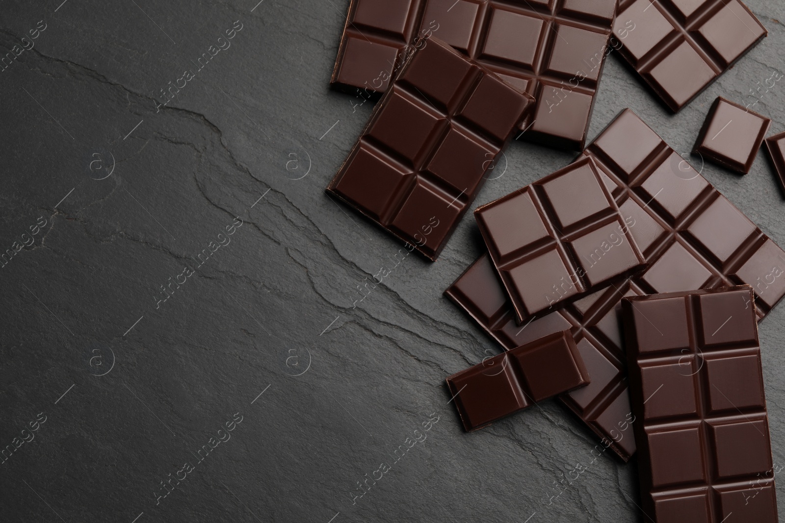 Photo of Delicious dark chocolate on black table, flat lay. Space for text