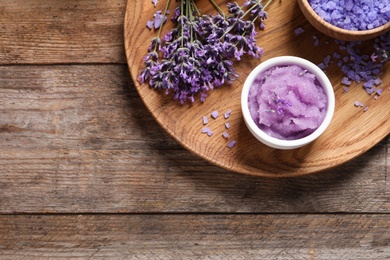 Plate with natural cosmetic products and lavender flowers on wooden table, top view. Space for text