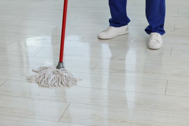 Photo of Man cleaning floor with mop indoors, closeup