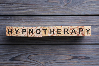 Photo of Blocks with word HYPNOTHERAPY on wooden background, flat lay