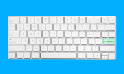 Keyboard with text KEYWORDS on blue background, top view