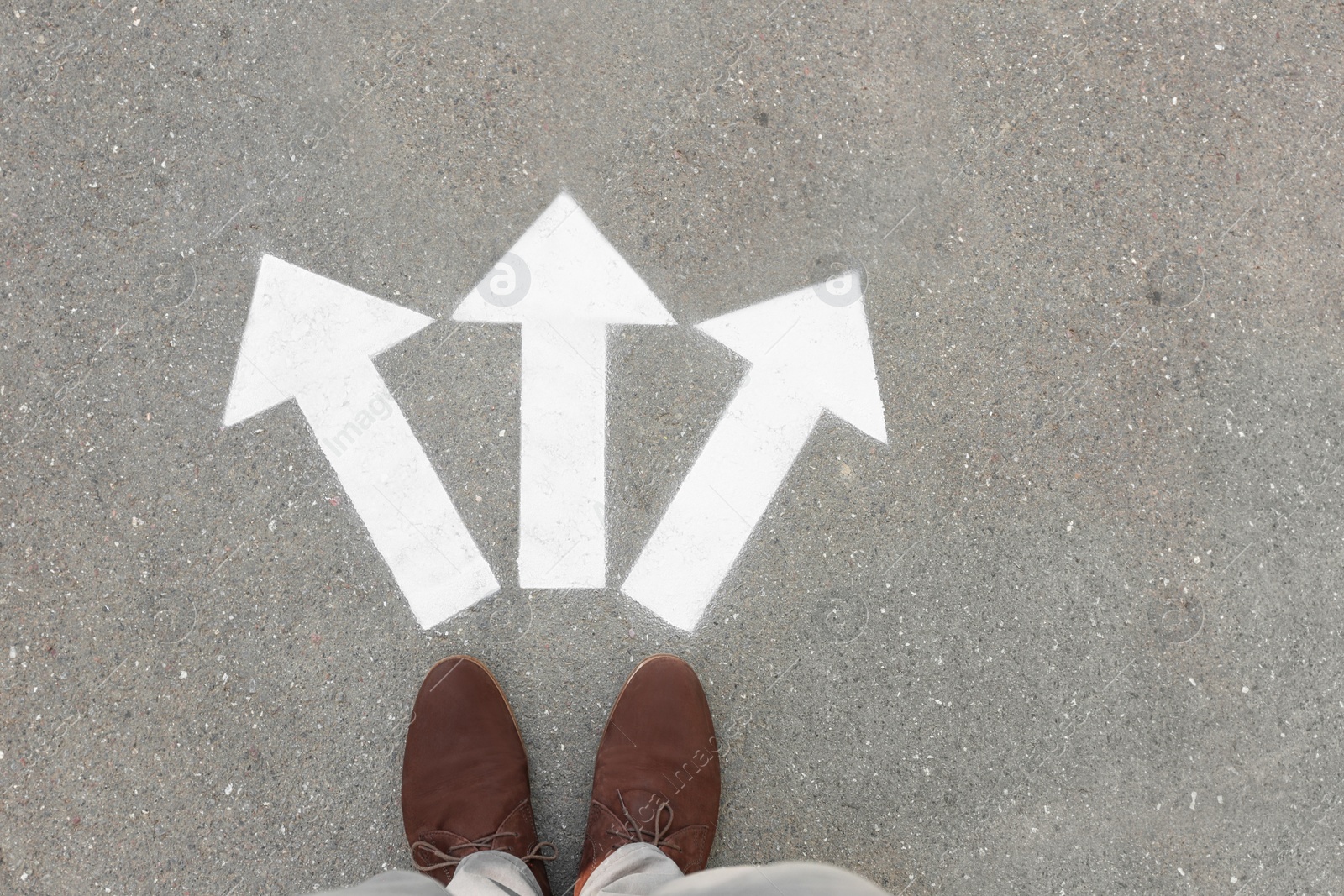 Photo of Man standing near arrows on asphalt, top view. Choice concept