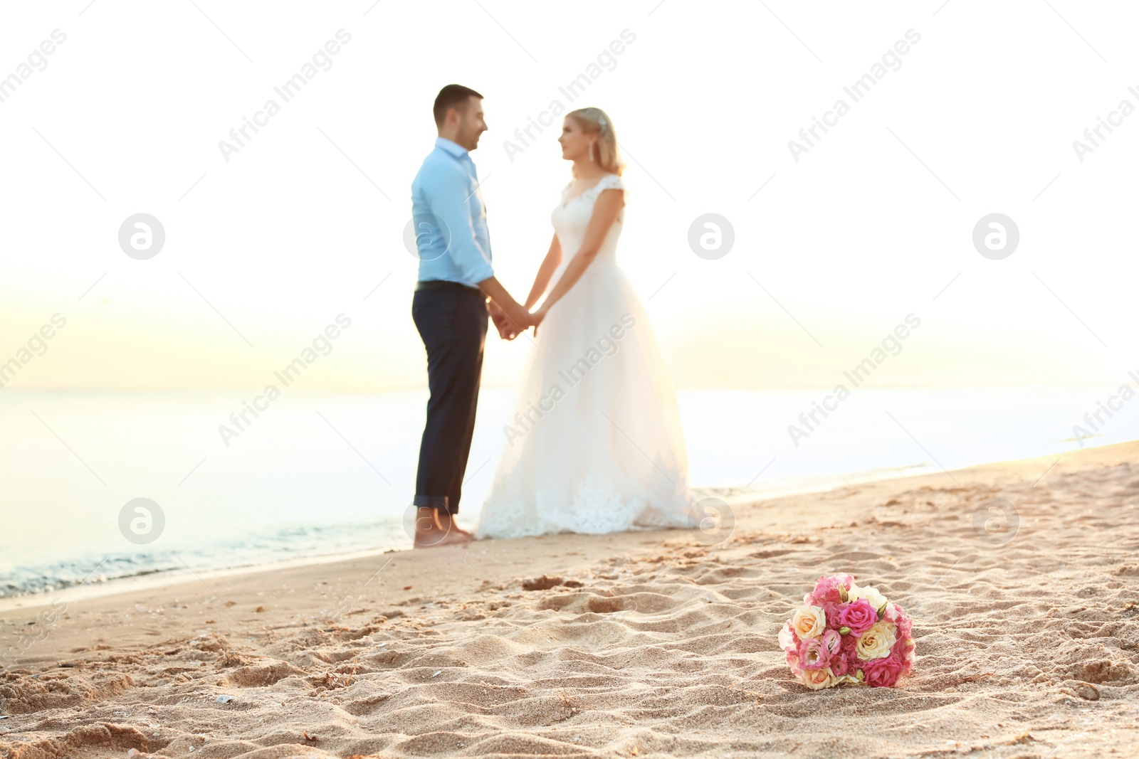 Photo of Bouquet and wedding couple on beach. Space for text