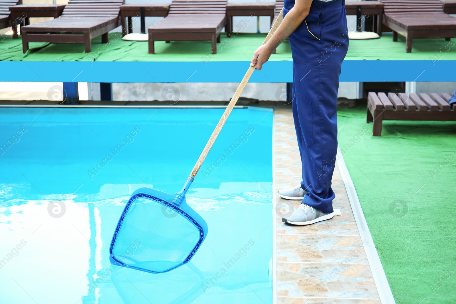 Photo of Male worker cleaning outdoor pool with scoop net