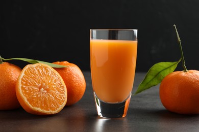 Photo of Delicious tangerine liqueur in glass and fresh fruits on grey table