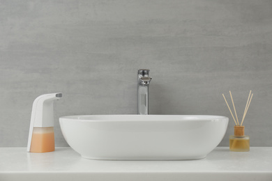 Modern automatic soap dispenser near sink in bathroom