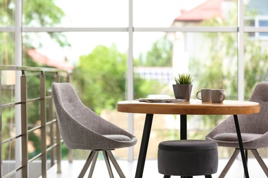 Stylish room interior with round table and comfortable chairs