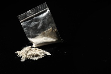 Photo of Plastic bag with hard drug on black background, closeup. Space for text