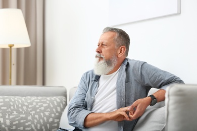 Photo of Portrait of handsome mature man sitting on sofa in room