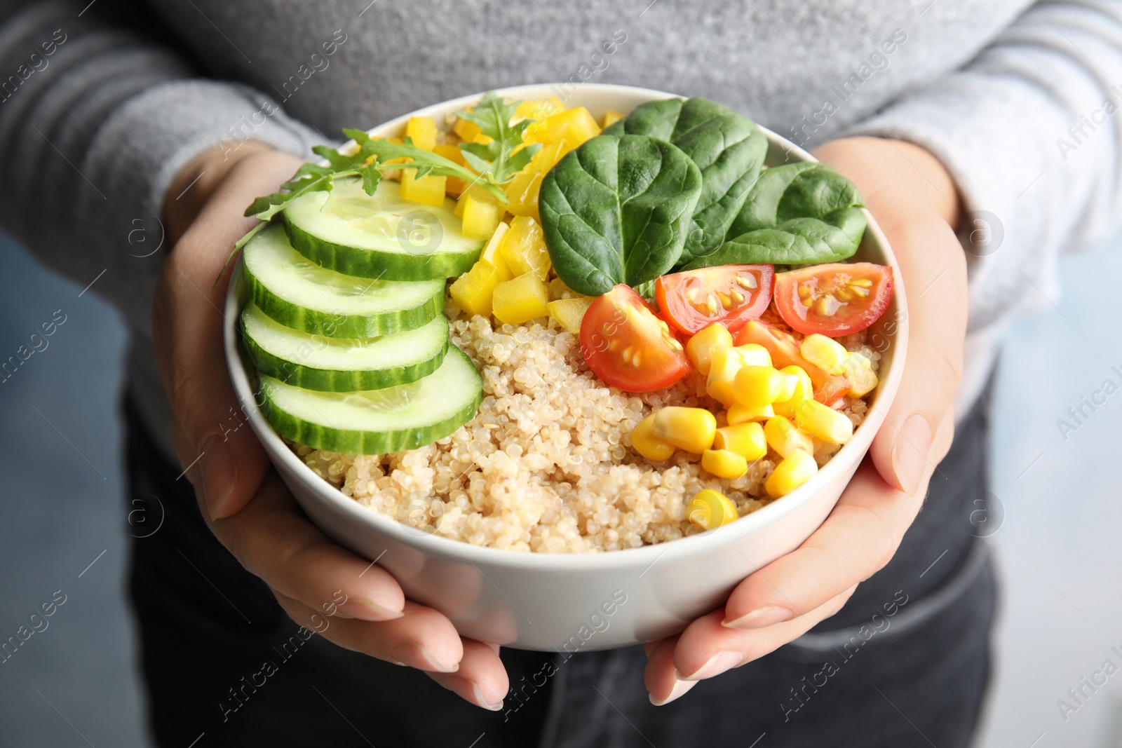 Photo of Woman holding bowl with healthy quinoa salad and vegetables, closeup