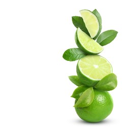 Stacked cut and whole limes with gren leaves on white background