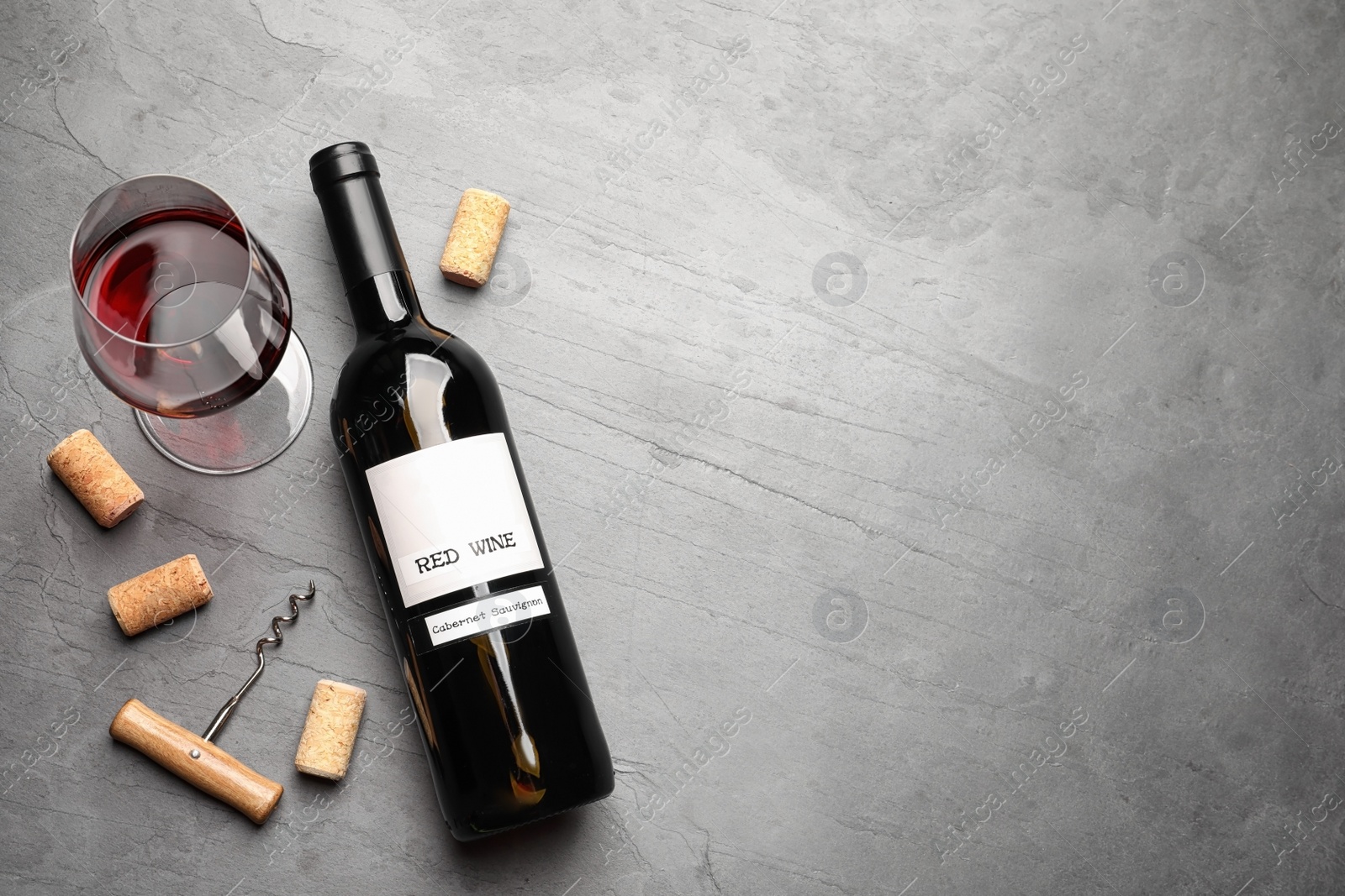 Photo of Flat lay composition with delicious red wine and corks on grey table. Space for text