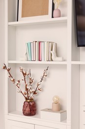 Shelves with different decor and fluffy cotton flowers indoors. Interior design