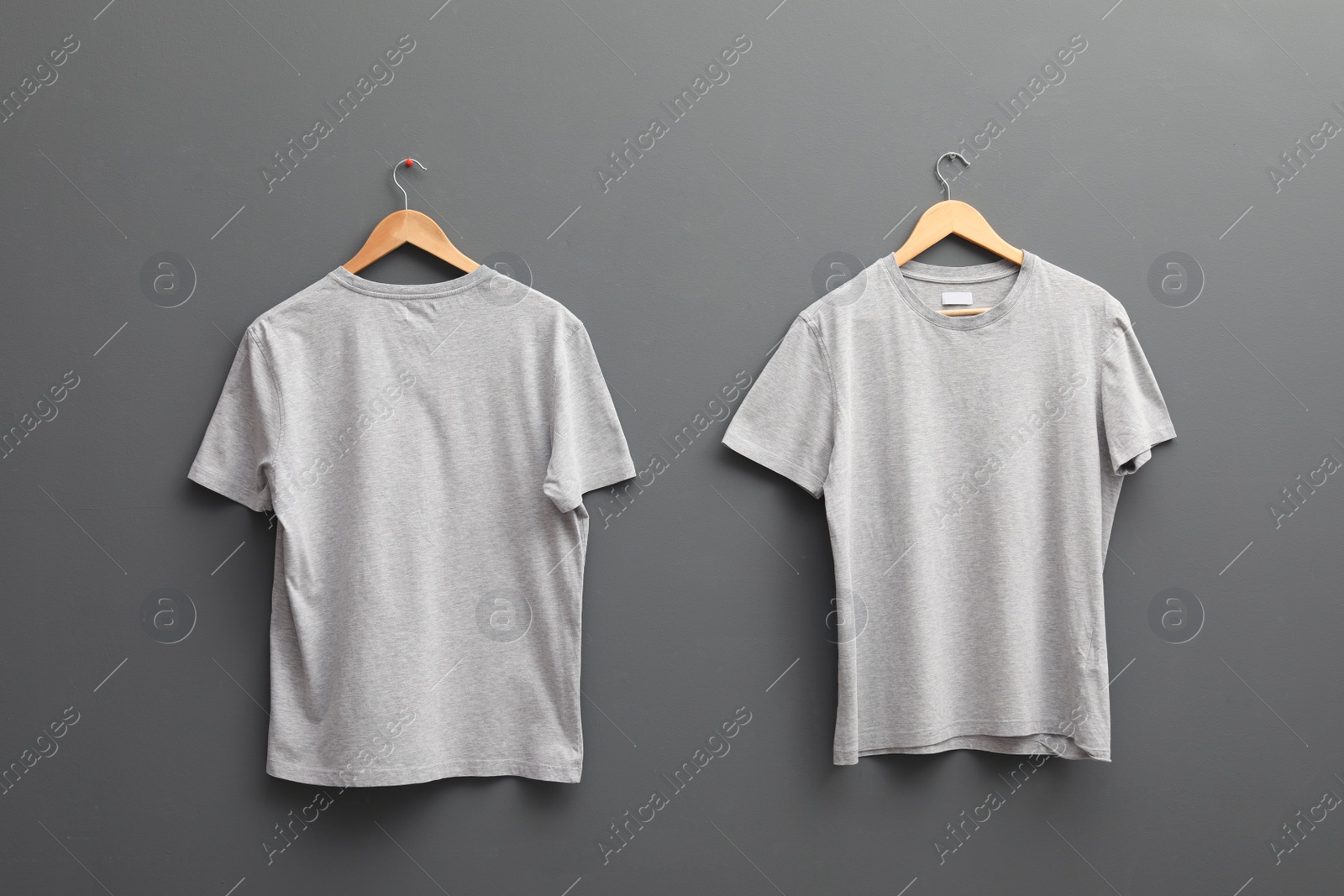 Photo of Hangers with blank t-shirts on grey background. Mockup for design