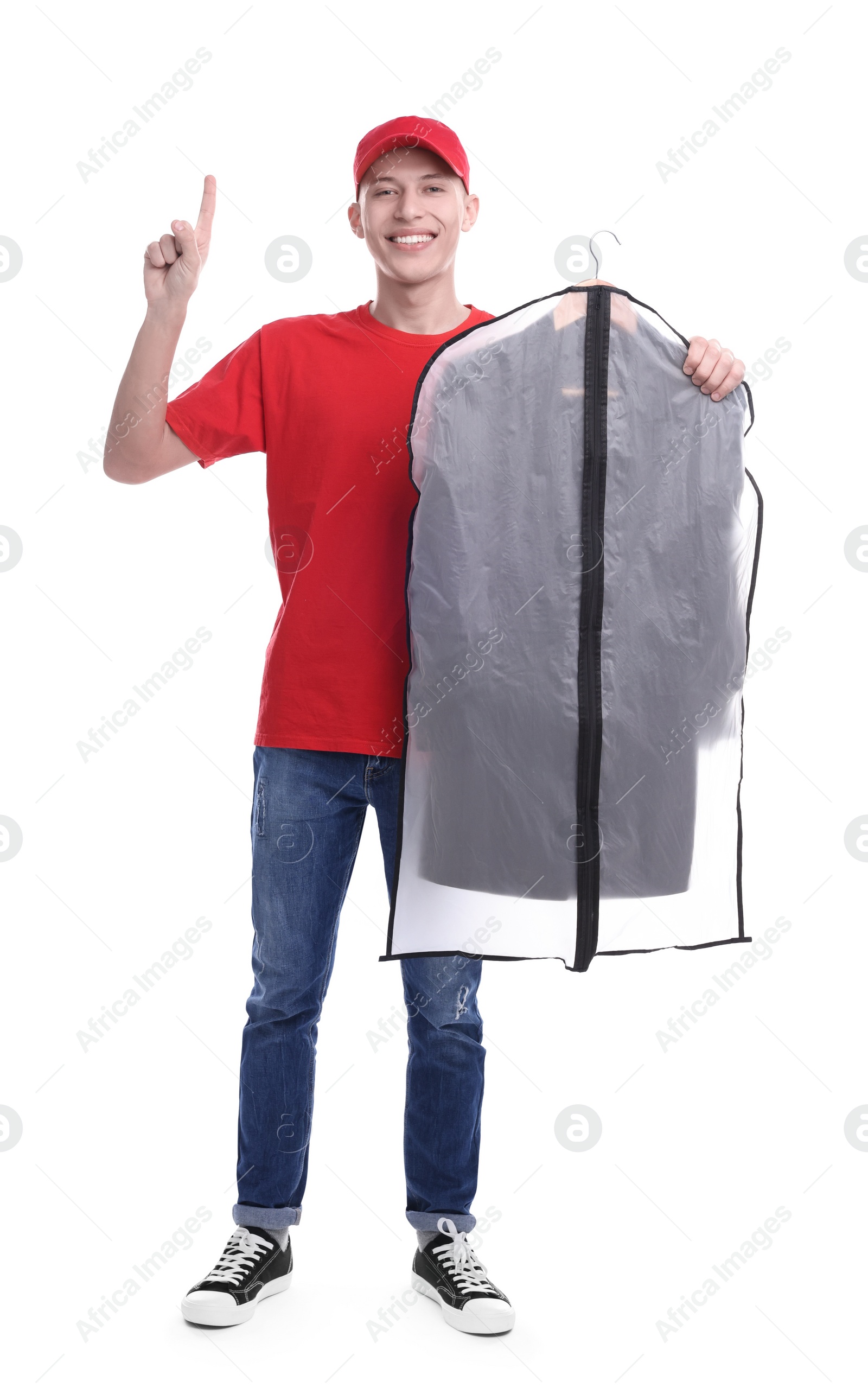 Photo of Dry-cleaning delivery. Happy courier holding garment cover with clothes and pointing at something on white background