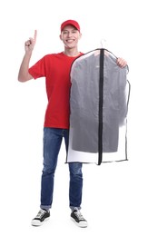 Dry-cleaning delivery. Happy courier holding garment cover with clothes and pointing at something on white background