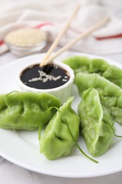 Delicious green dumplings (gyozas) and soy sauce on white marble table, closeup