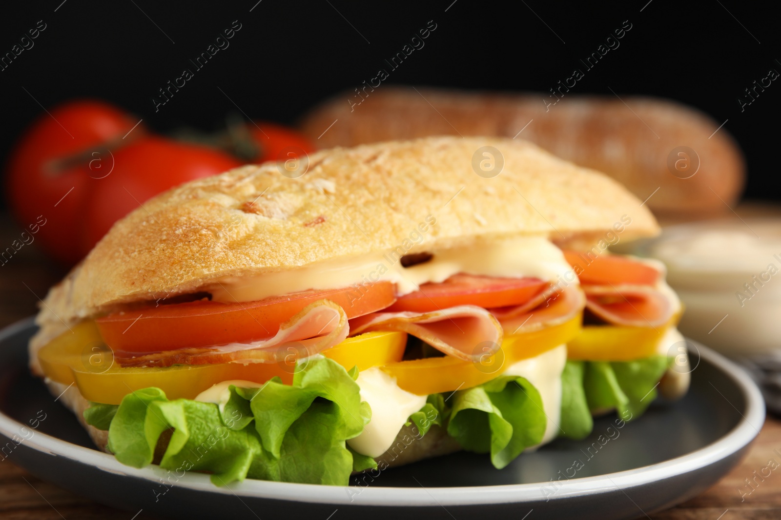 Photo of Delicious sandwich with vegetables, ham and mayonnaise served on wooden table, closeup