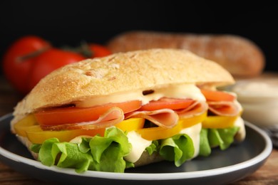 Delicious sandwich with vegetables, ham and mayonnaise served on wooden table, closeup