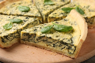 Photo of Cut delicious spinach pie on wooden board, closeup