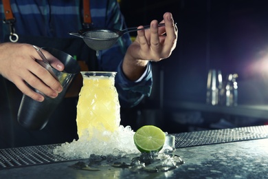 Photo of Barman making tropical cocktail at counter in pub, closeup. Space for text