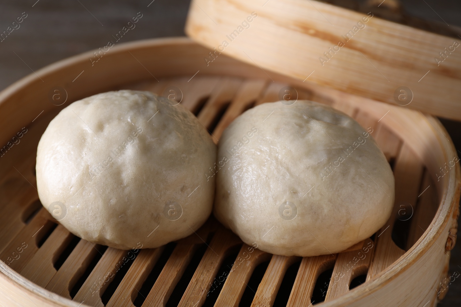 Photo of Delicious Chinese steamed buns in bamboo steamer on table, closeup