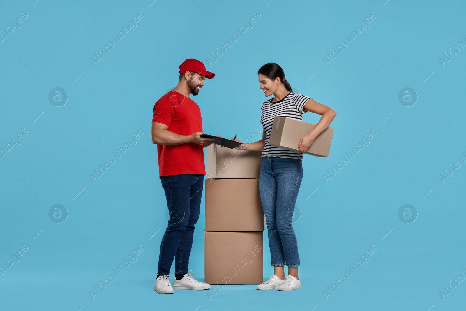 Photo of Smiling woman signing order receipt on light blue background. Courier delivery