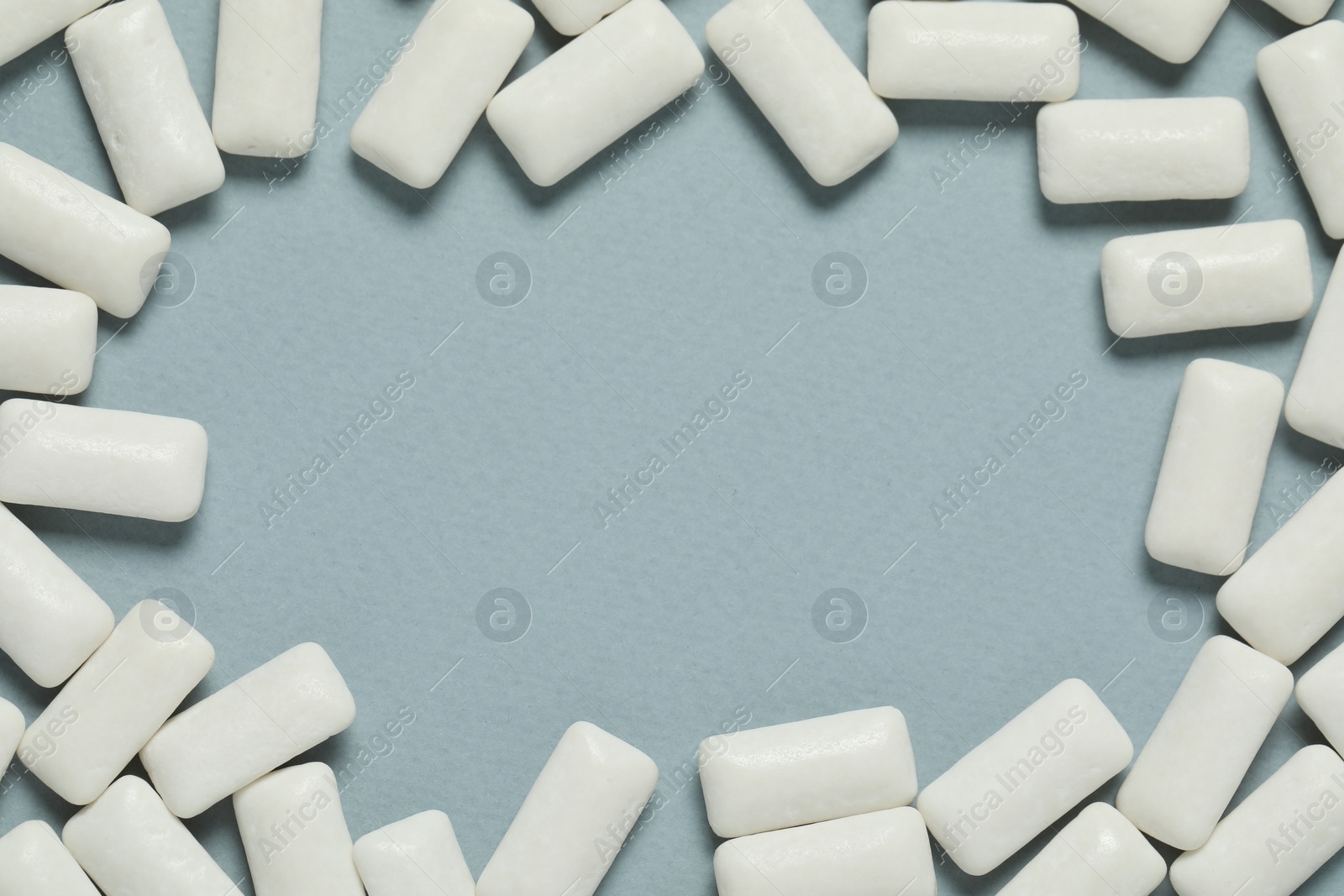 Photo of Frame made of tasty white chewing gums on light blue background, flat lay. Space for text