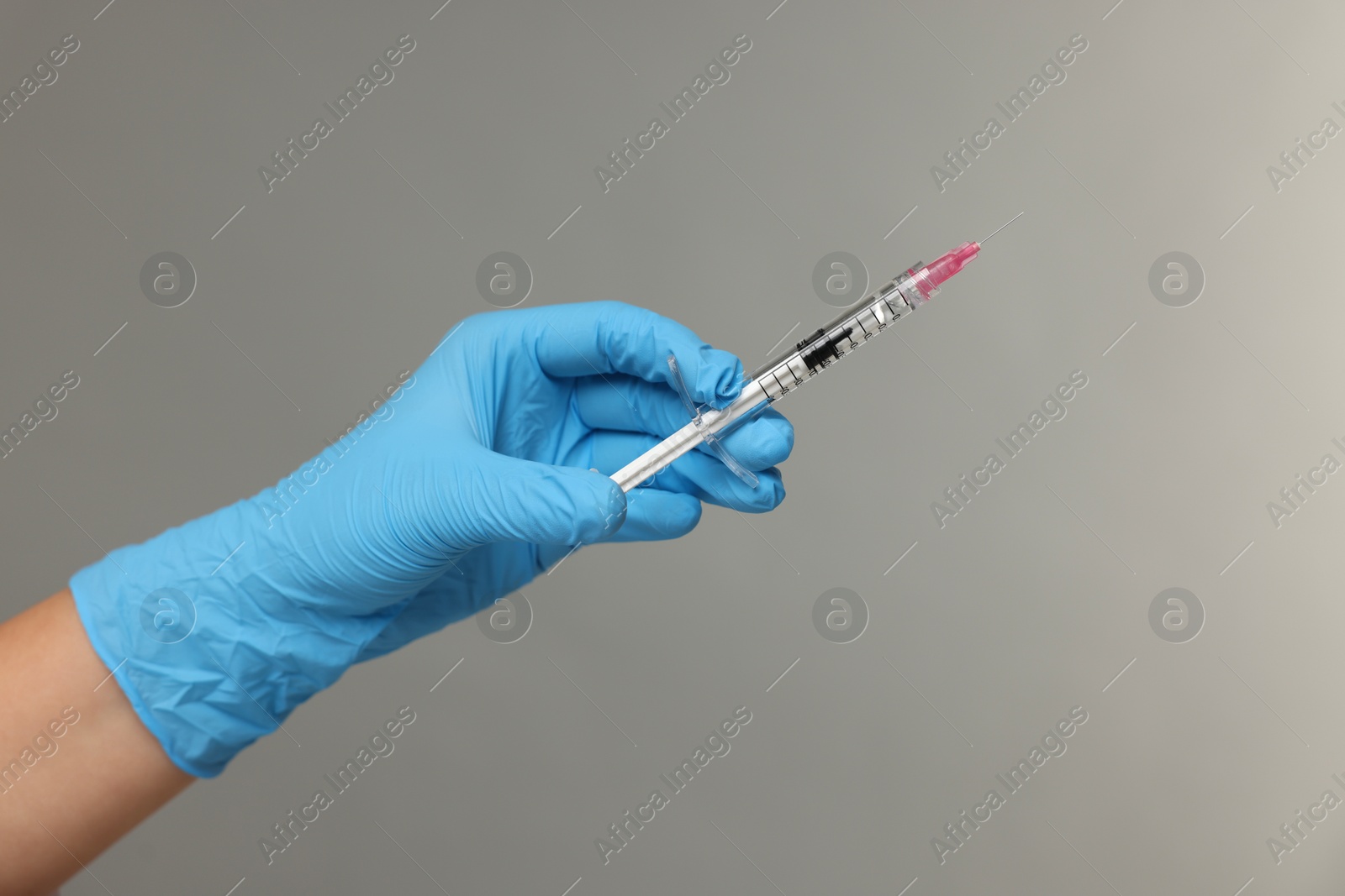 Photo of Doctor holding syringe on grey background, closeup