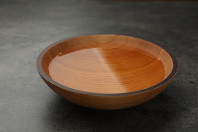Photo of Wooden bowl with water on grey table, closeup