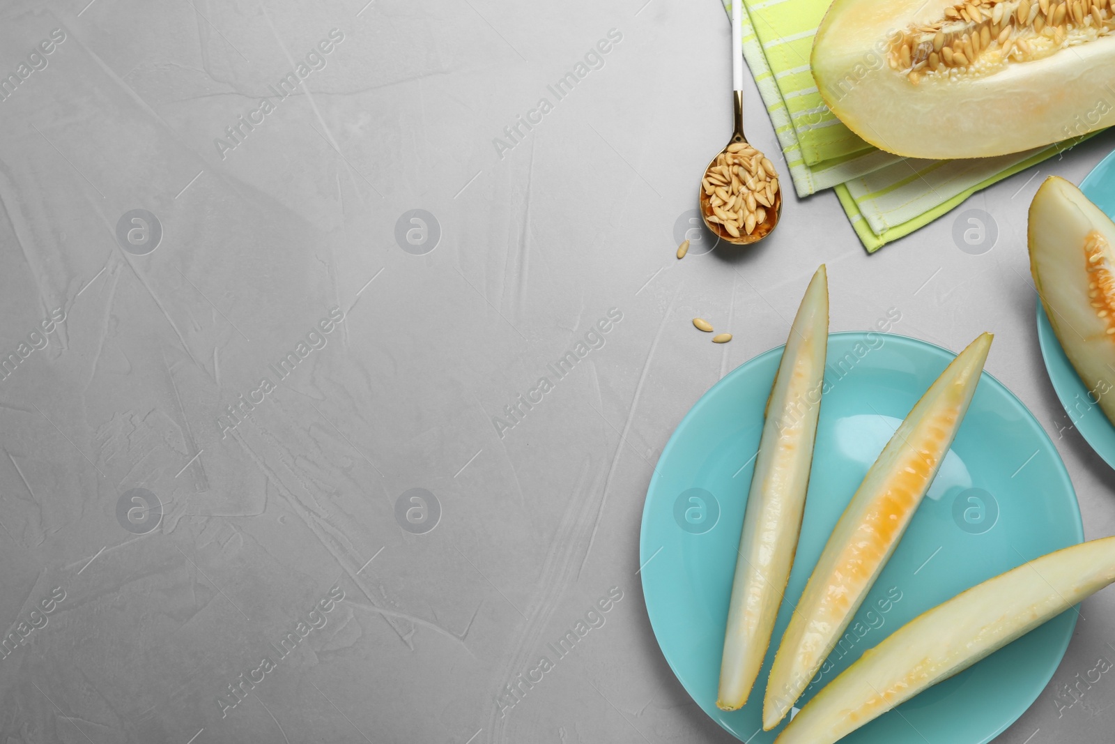 Photo of Slices of delicious honey melon on light grey table, flat lay. Space for text