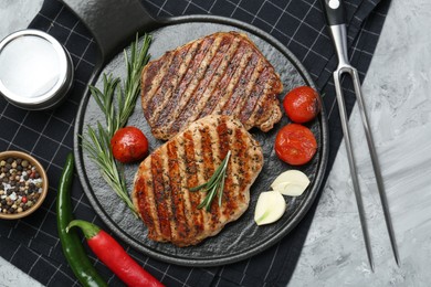 Photo of Delicious grilled pork steaks with spices and meat fork on table, top view