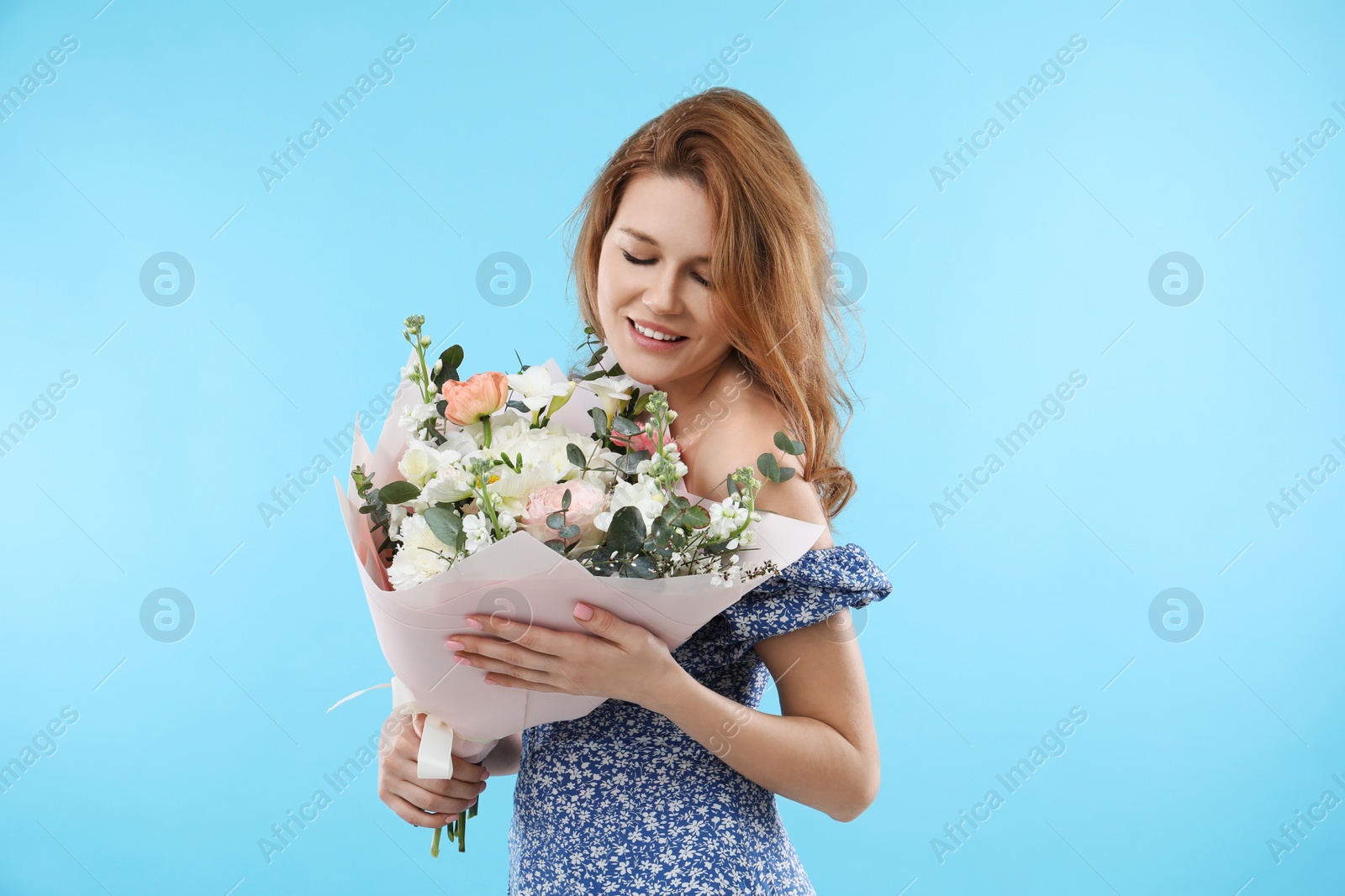 Photo of Happy woman with bouquet of beautiful flowers on light blue background