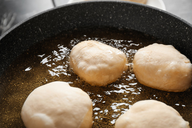 Photo of Cooking delicious donuts in hot oil, closeup