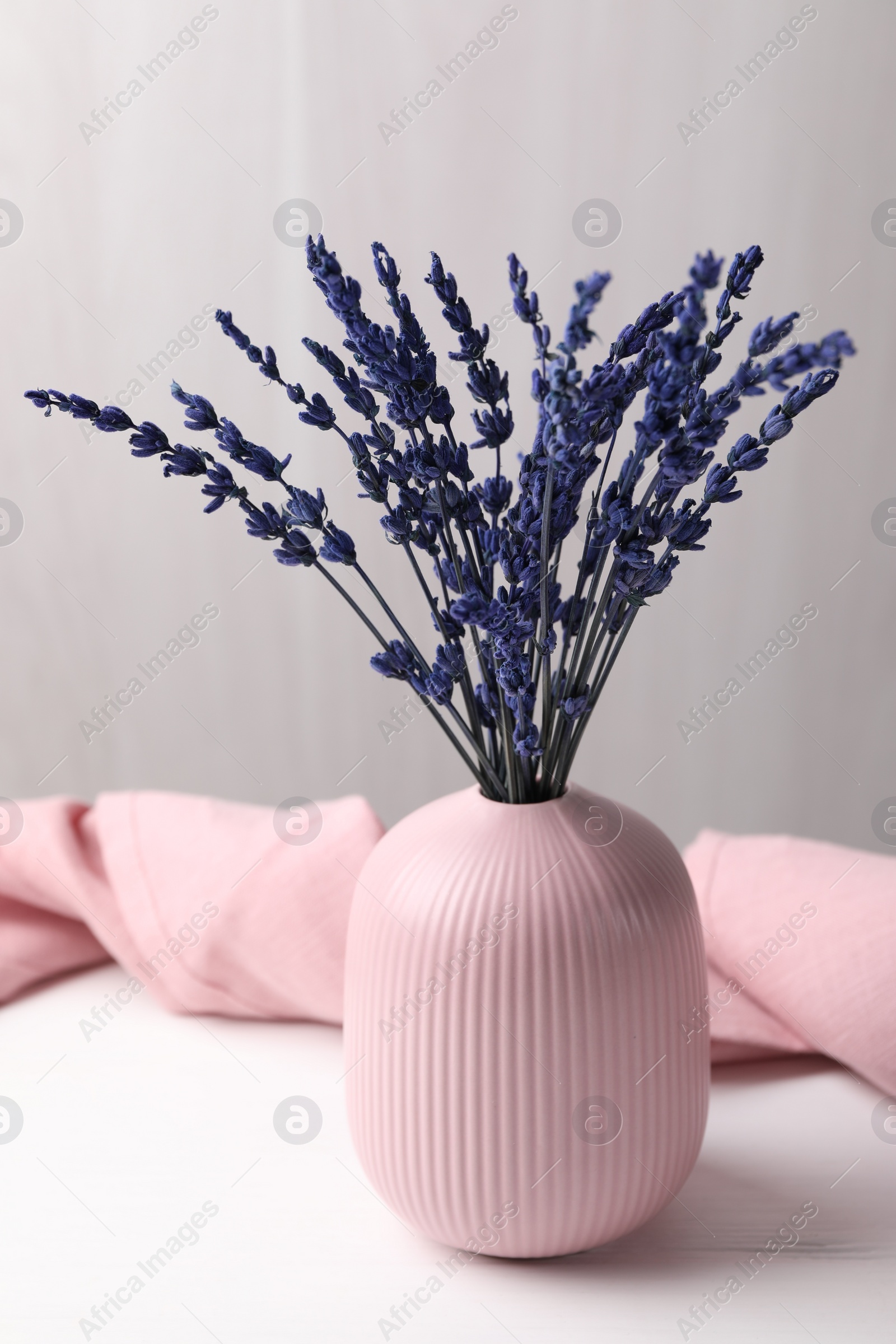 Photo of Bouquet of beautiful preserved lavender flowers on white wooden table near grey wall