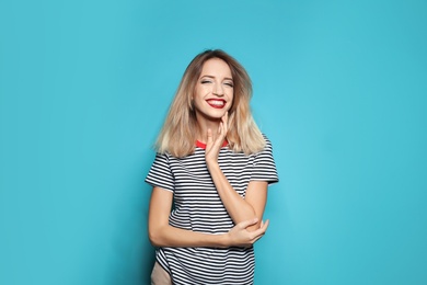 Beautiful young woman with healthy long blonde hair on color background