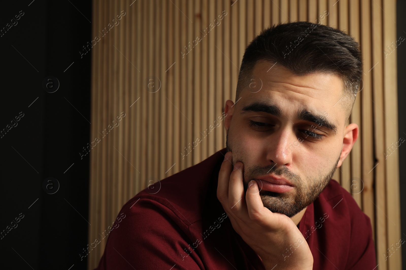 Photo of Sad young man at home. Space for text