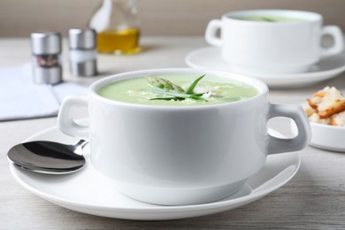 Photo of Delicious asparagus soup with green onion served on white wooden table, closeup