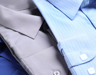 Photo of Stylish shirts as background, closeup. Dry-cleaning service