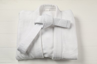 Photo of White karate belt and kimono on wooden background, top view