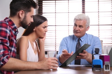 Senior notary working with young couple in office