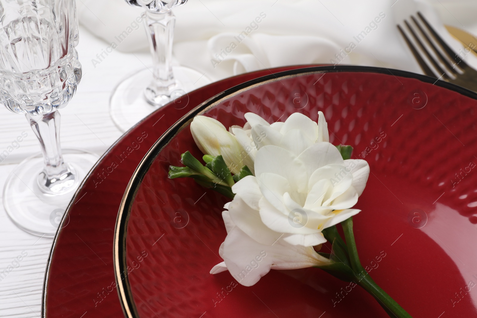 Photo of Dishes with flower and glasses on white table, closeup