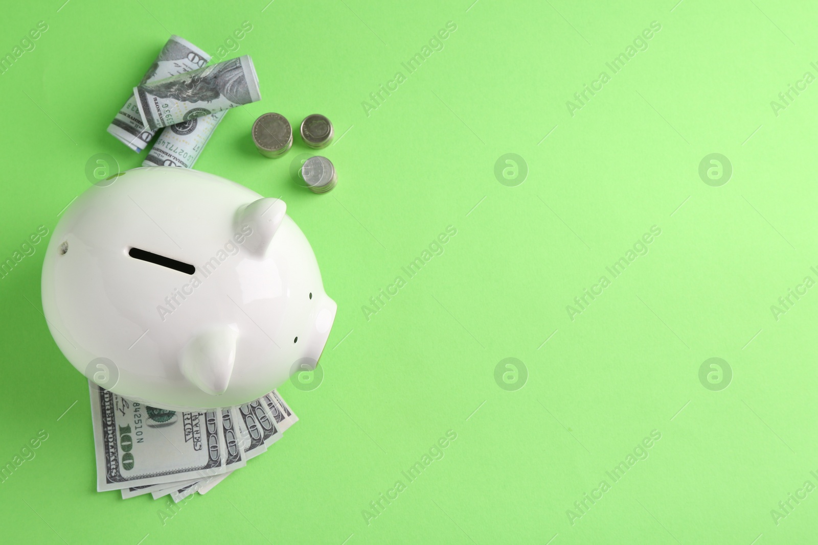 Photo of Financial savings. Piggy bank, dollar banknotes, coins and calculator on green background, flat lay. Space for text