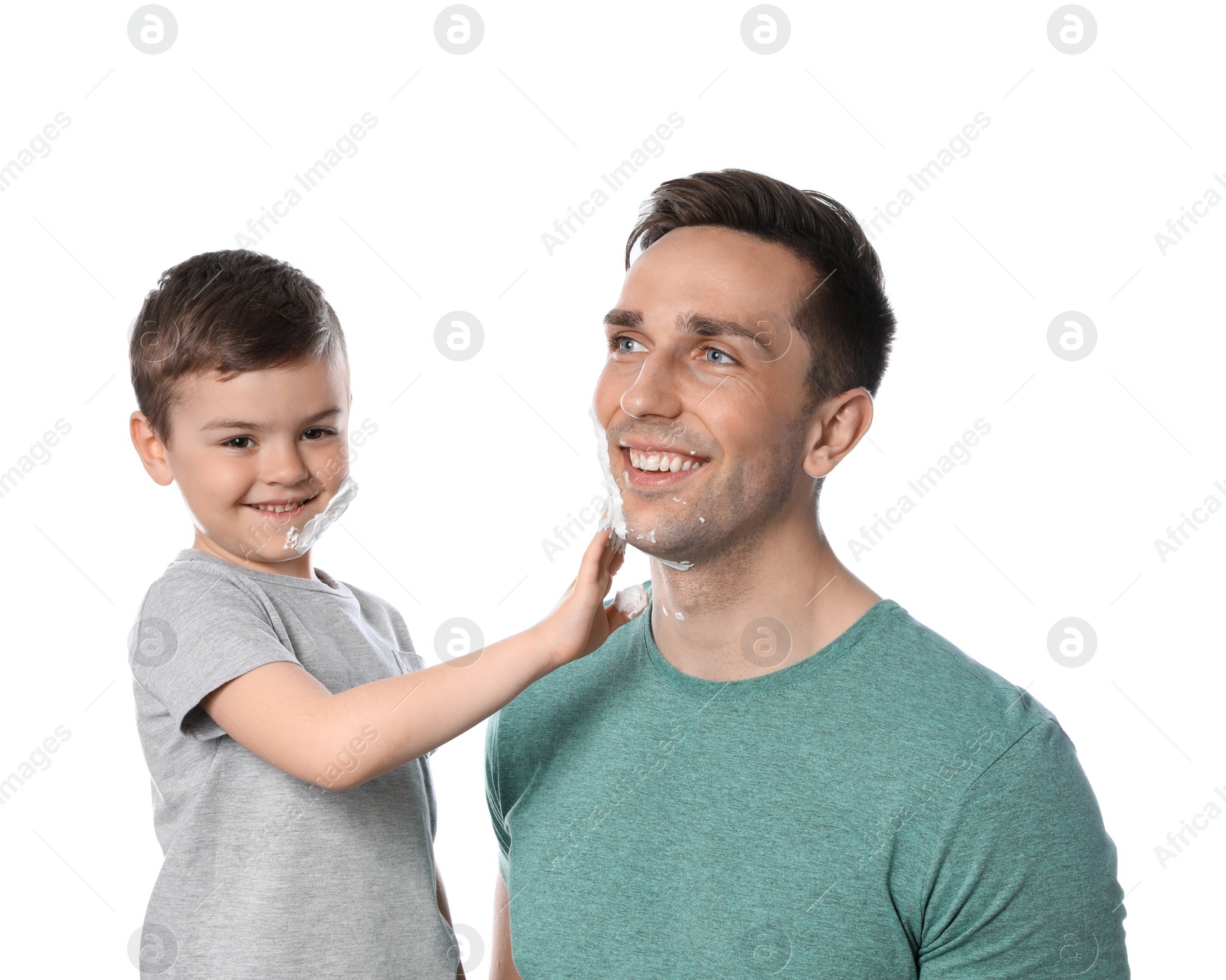 Photo of Little son applying shaving foam onto dad's face against white background