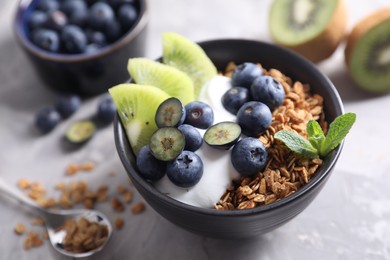 Photo of Tasty granola in bowl served on gray table, closeup