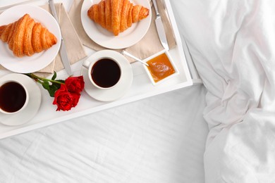 Tasty breakfast served in bed. Fresh croissants, coffee and honey on tray, top view. Space for text